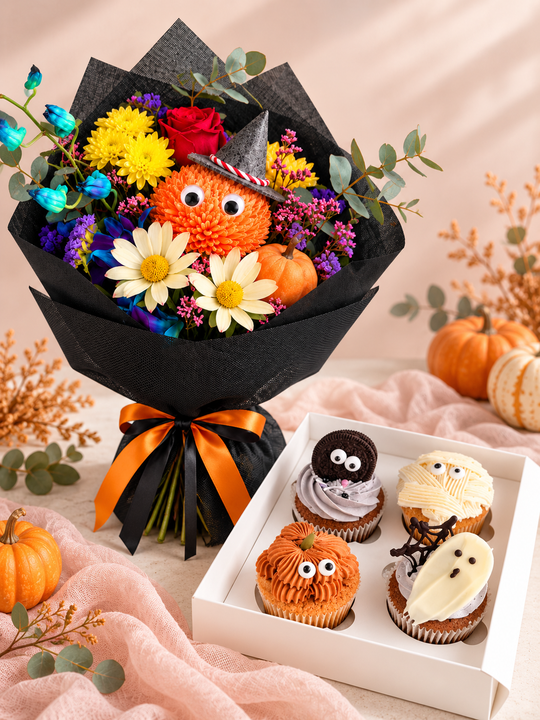 
                  
                    A Halloween-themed gift set featuring a colorful flower bouquet with an orange pumpkin decoration, small pumpkins, white daisies, yellow and red flowers, and a black paper wrap with an orange ribbon, alongside a white box of four decorated cupcakes with spooky faces.
                  
                
