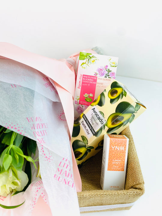 Gift basket with avocado-themed products and flowers on a white background