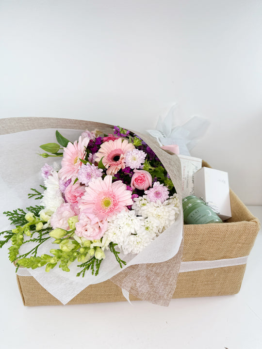 
                  
                    Bouquet of flowers in a box with candle, chocolate and tea on a white background
                  
                