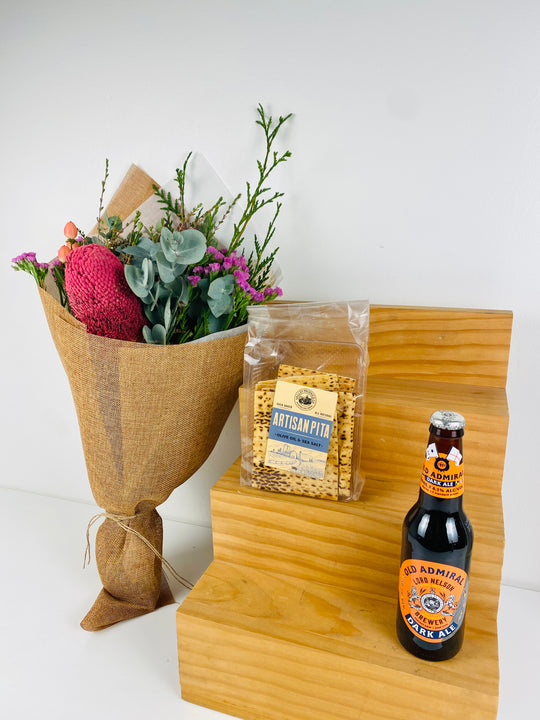Bouquet of flowers, bag of popcorn, and bottle of beer on a wooden stand with a white background