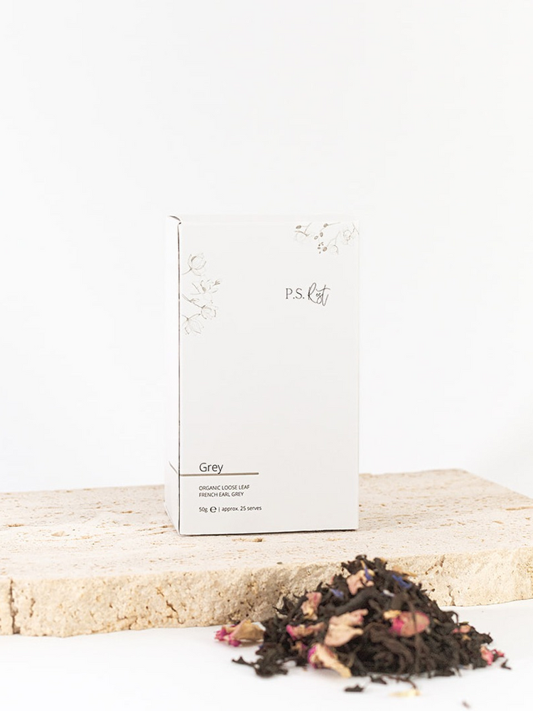 
                  
                    Tea packaging labeled 'PS' with loose tea leaves on a wooden surface
                  
                