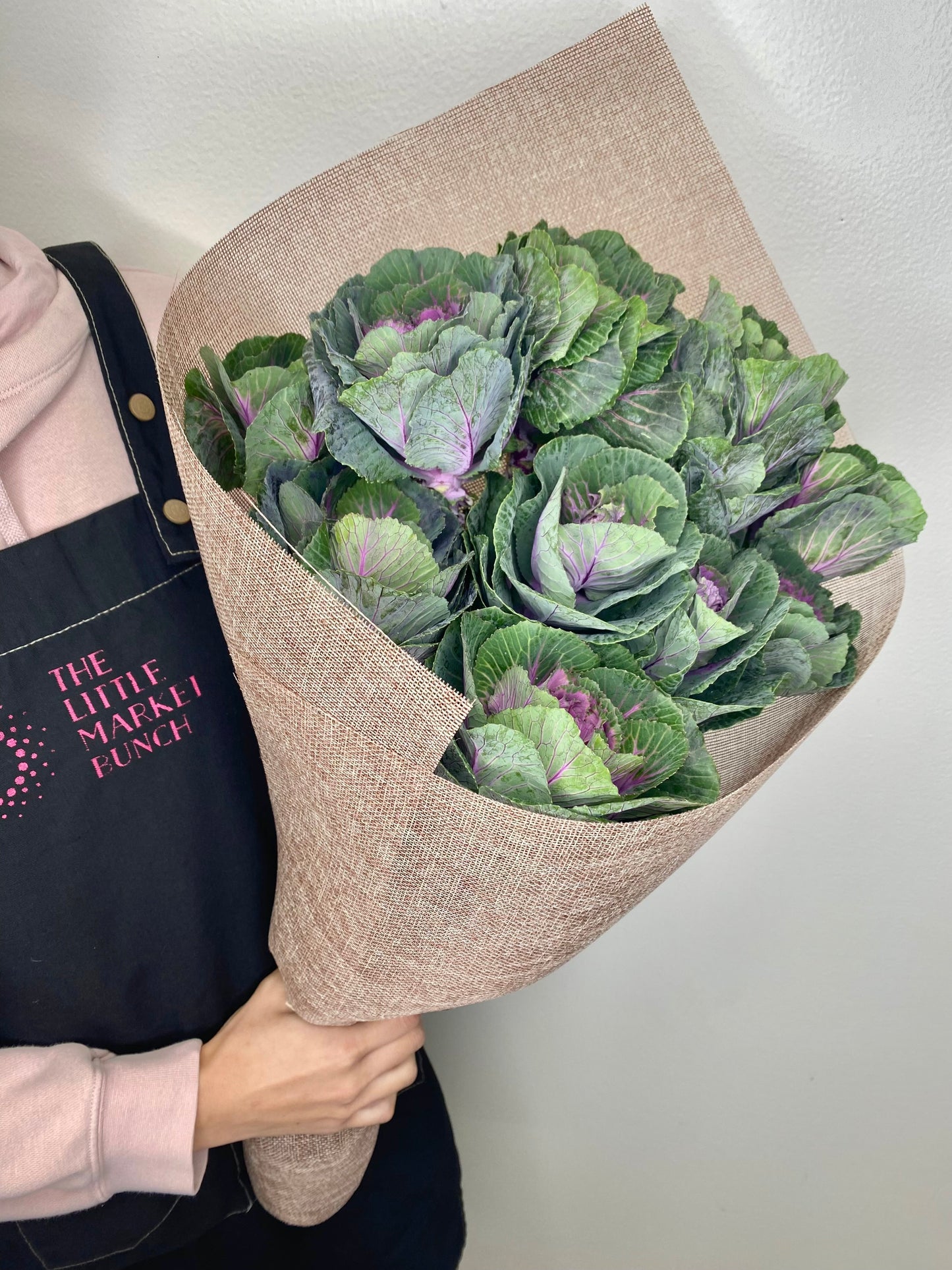 This image features a bouquet of ornamental kale, beautifully arranged with lush, textured leaves in shades of green and hints of purple. Wrapped in natural, brown burlap-style paper, the bouquet showcases a unique and earthy aesthetic.
shot by The Little Market Bunch, Melbourne.