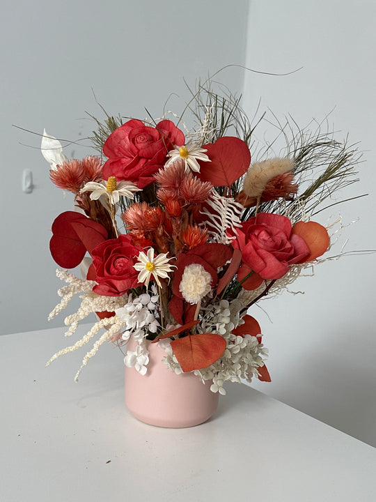 
                  
                    A pot of dried flowers on a mannequin head against a plain background
                  
                
