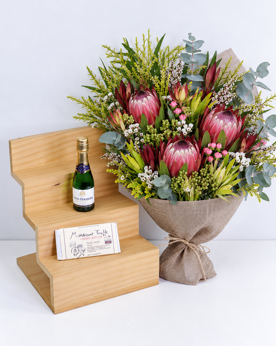 
                  
                    Bouquet of flowers, French sparkling wine , and a chocolate on a wooden stand with a white background
                  
                