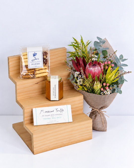 Bouquet of flowers, cookies, jam and a chocolate  on a wooden stand with a white background