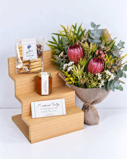 Bouquet of flowers, cookies, jam and a chocolate  on a wooden stand with a white background