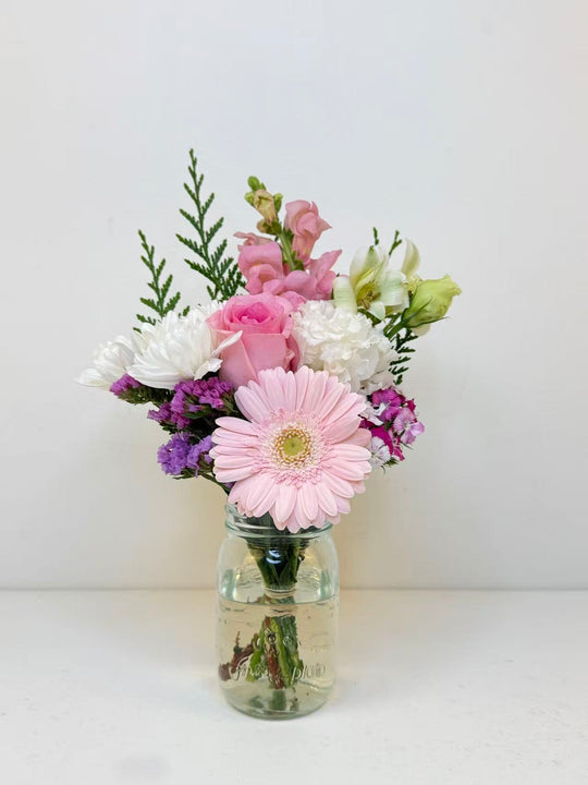
                  
                    Bouquet of flowers in a clear jar on a white background
                  
                