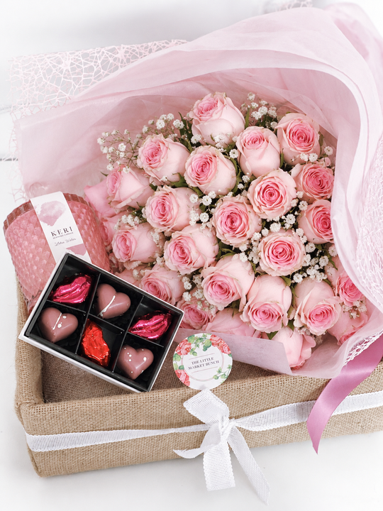 A gift box containing a pink rose bouquet, six packs of chocolate hearts, and a fragrant premium candle.